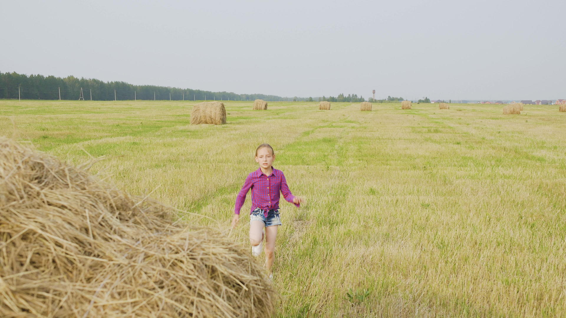 快乐的小女孩在阳光明媚的干草地上奔跑视频的预览图