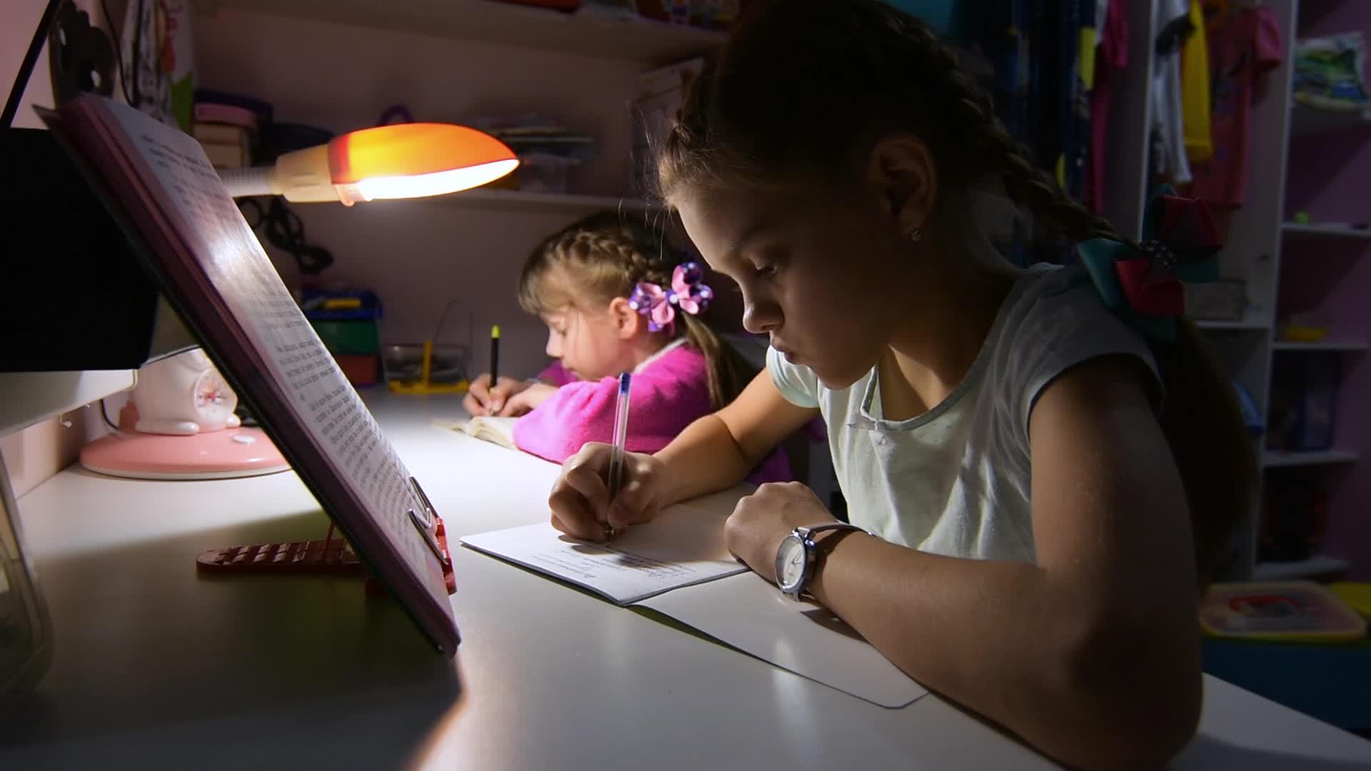 两个女孩在深夜做作业灯照在桌子上视频的预览图