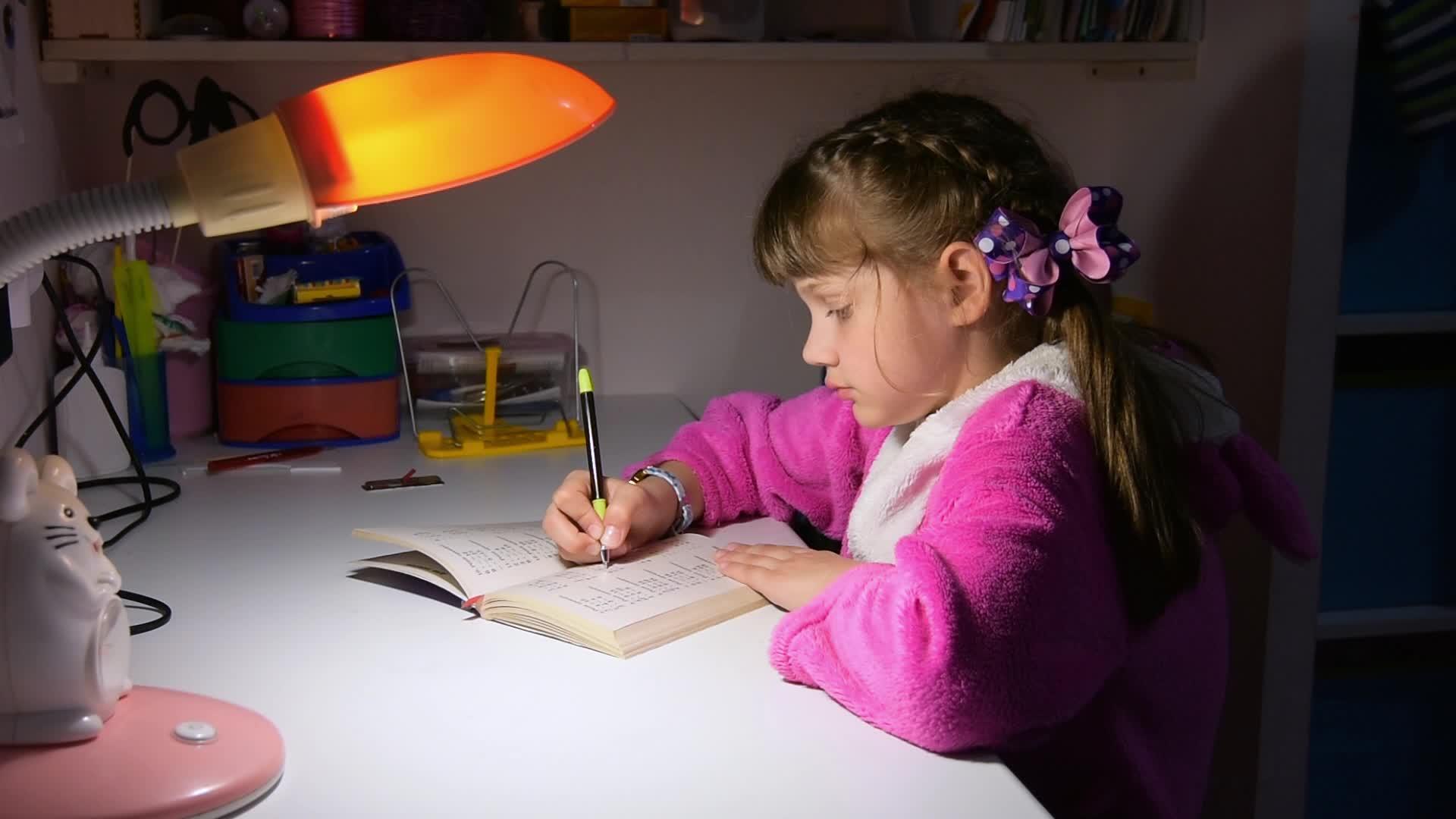 一个女孩深夜在桌灯下做作业视频的预览图