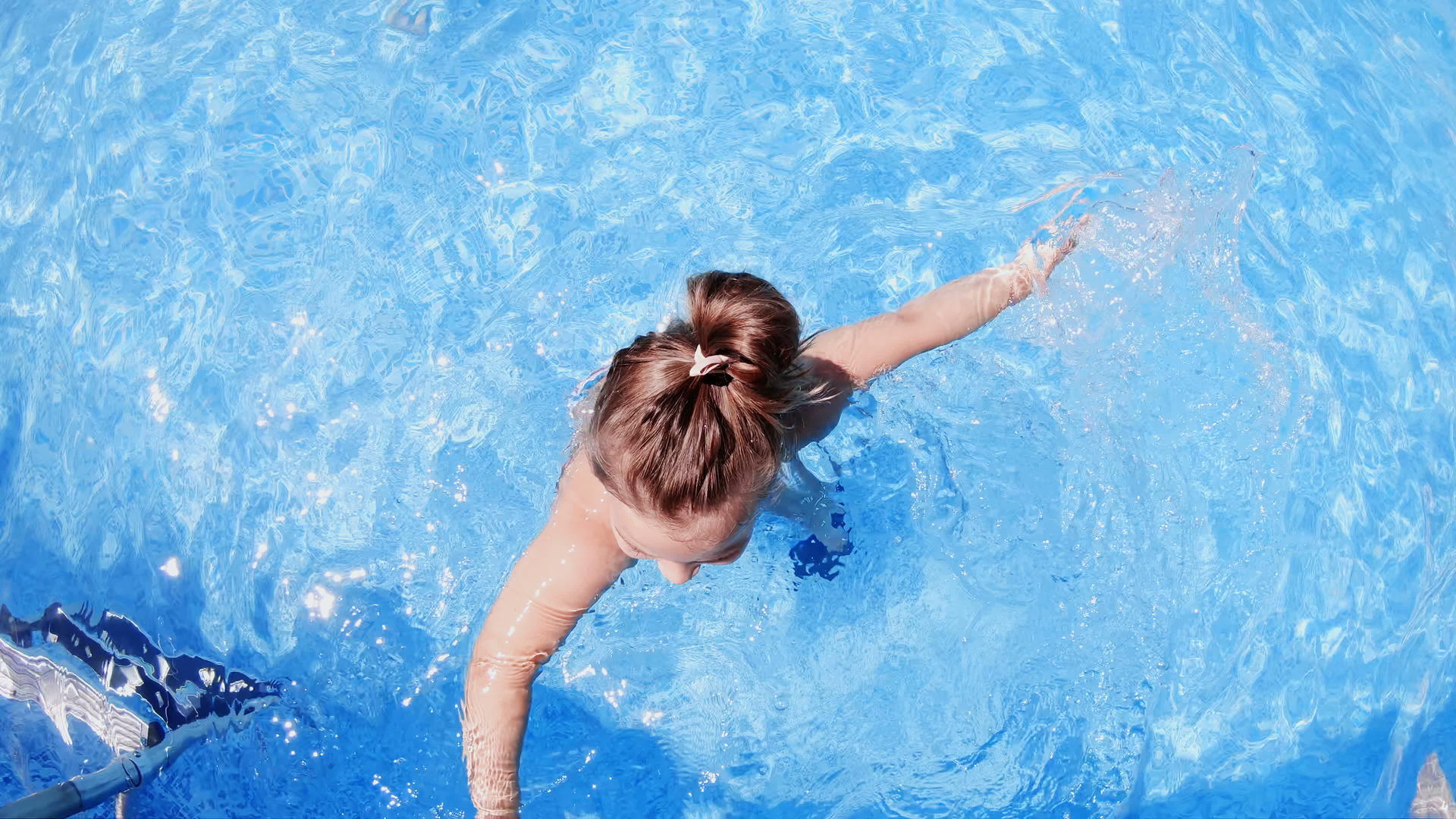 快乐的小女孩在游泳池的顶视图中慢慢地在腿上慢慢地移动视频的预览图
