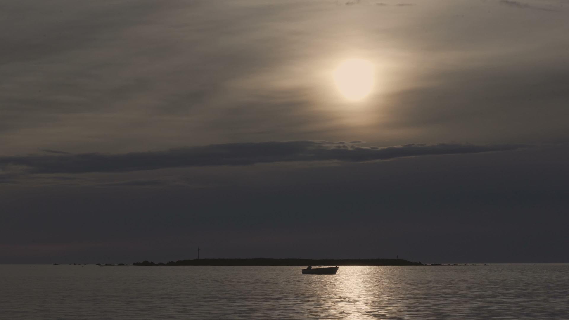 日出或日落时在夜空的阴云下渔船在海湾里视频的预览图