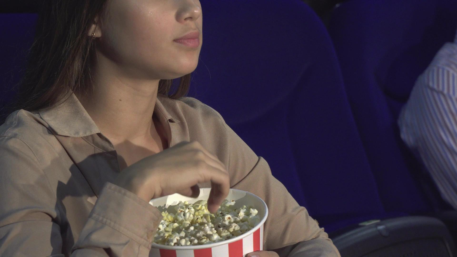 一个女孩如何吃爆米花和特写显示沉默的迹象？视频的预览图