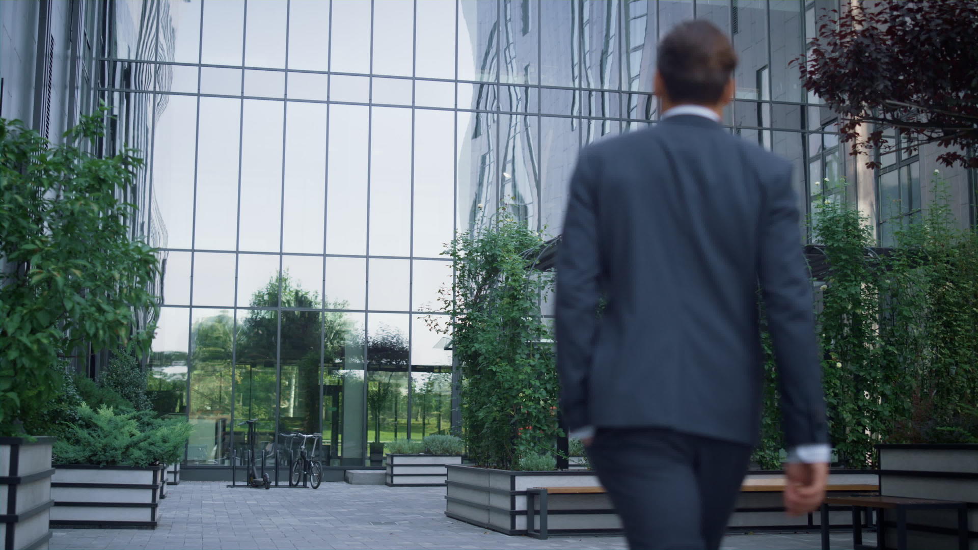 自信的商务人士独自走在商务中心的花园里视频的预览图