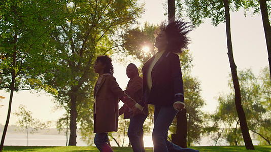 小孩牵着父母的手在绿色公园散步视频的预览图