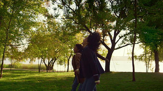 幸福的父母和孩子手牵手走在秋天的城市花园里从侧面看视频的预览图