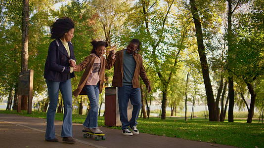 父母在公园里教女孩骑长板板视频的预览图