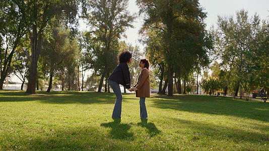 母亲牵着女儿的手轻轻地抚摸着阳光明媚的绿色公园田野视频的预览图