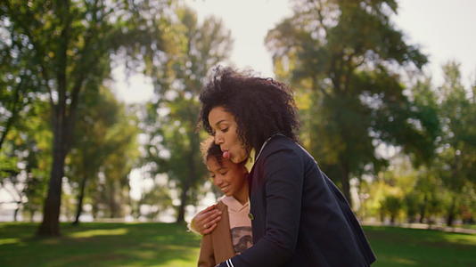 快乐的妈妈在公园里用智能手机和可爱的女儿自拍视频的预览图
