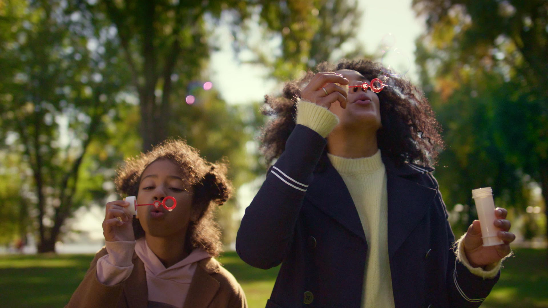 父母和孩子在阳光明媚的绿色公园里吹肥皂泡泡视频的预览图