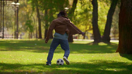 男人在温暖的春天踢足球公园视频的预览图