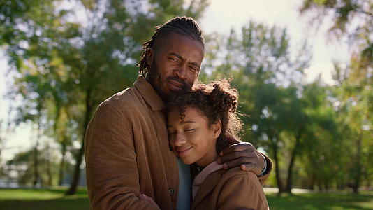 慈爱的父亲拥抱着女儿阳光明媚的公园肖像视频的预览图