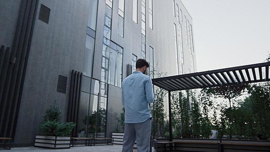 商务人士发短信站在现代玻璃办公大楼视频的预览图