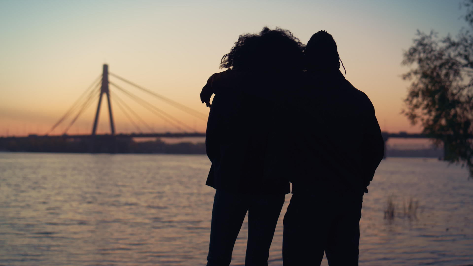 剪影夫妇在河桥视图上看日落视频的预览图