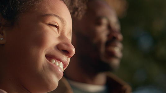 微笑的小女孩肖像和父亲站在一起享受黄金的傍晚阳光视频的预览图