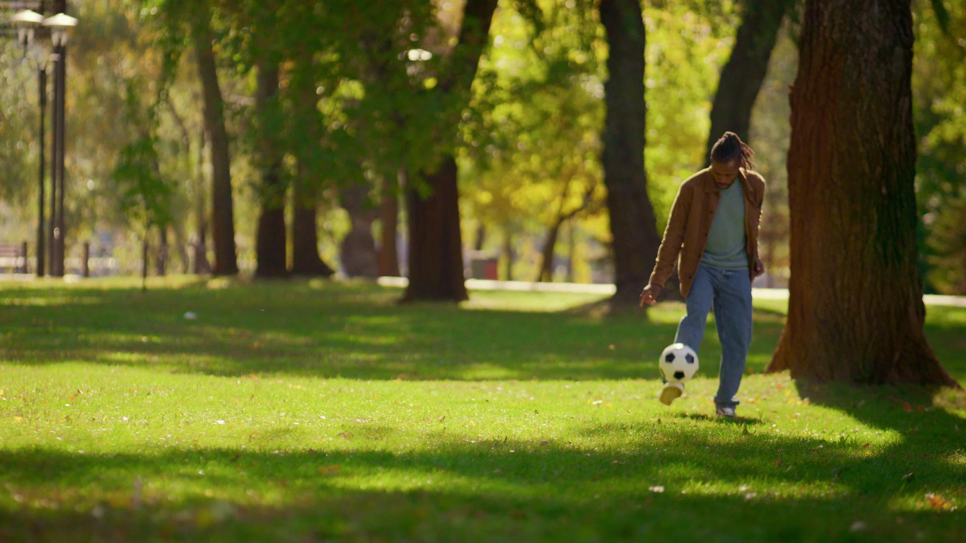快乐的父亲独自在阳光明媚的公园里踢足球视频的预览图