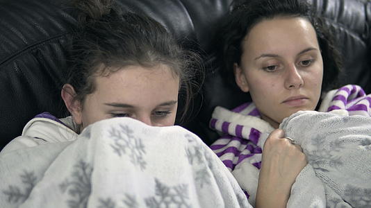 两个女朋友在沙发上看恐怖电视节目视频的预览图