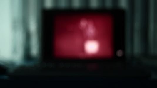 恐怖电影在黑暗中的笔记本电脑屏幕上播放视频的预览图