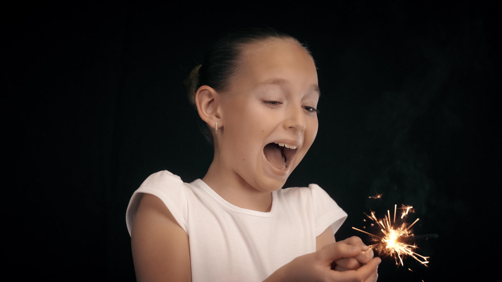 胆小的女孩手里拿着黑色背景的火花和热火花视频的预览图