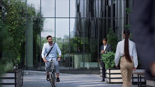 微笑的商人在现代办公楼骑自行车视频的预览图