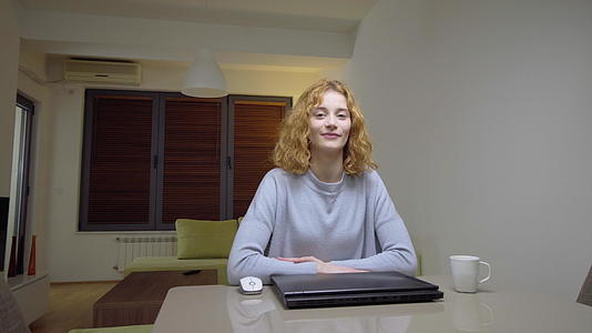 可爱的女孩坐在客厅的桌子上在家里的笔记本电脑前工作视频的预览图