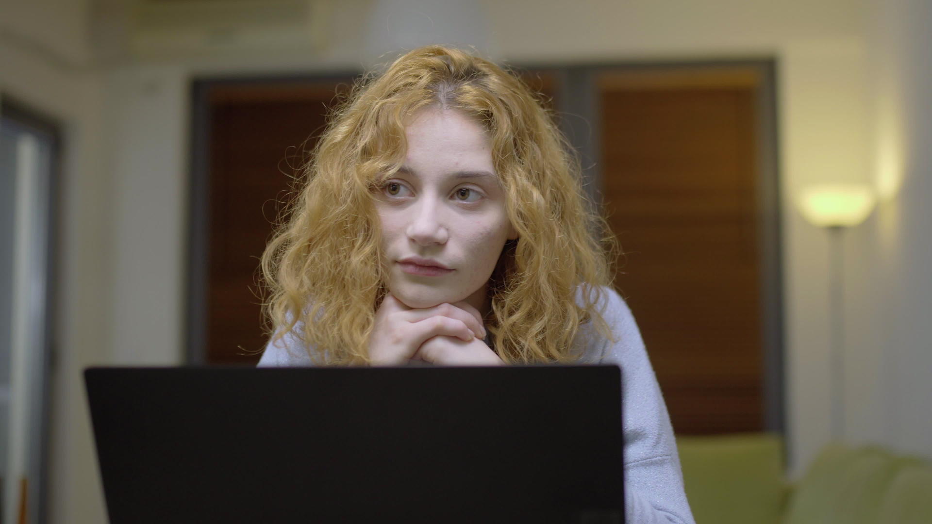 可爱的女孩坐在客厅的桌子上把头发放在笔记本电脑前视频的预览图