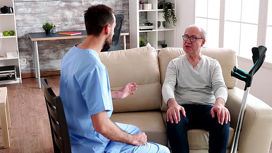 年轻的胡子医生和老人交谈视频的预览图