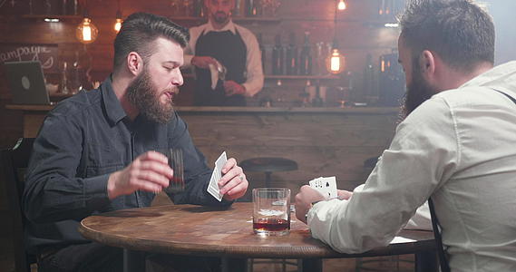 和朋友打牌时喝威士忌胡子的男人视频的预览图