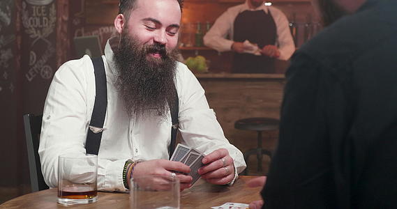 长胡子长胡子的人笑着和朋友玩牌视频的预览图