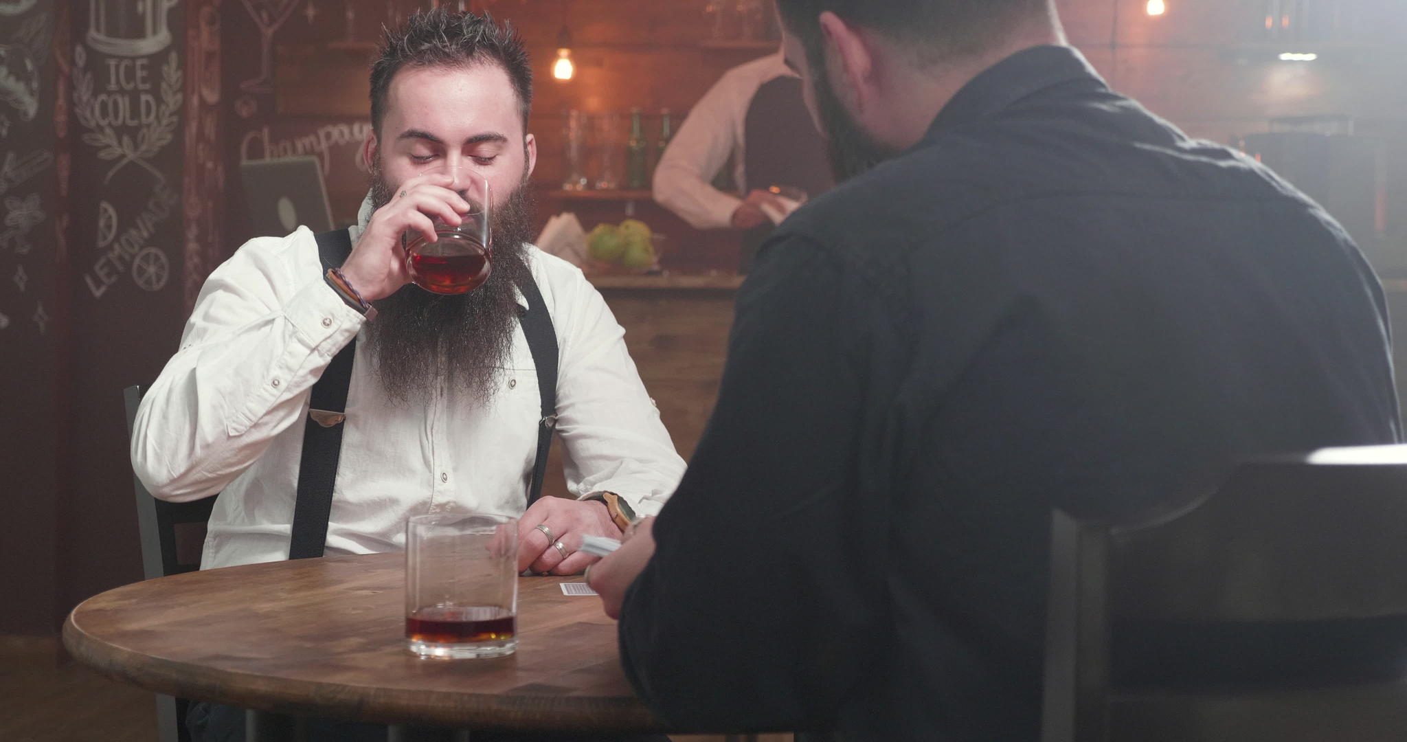 两个大胡子男人在酒吧喝酒开始玩纸牌游戏视频的预览图