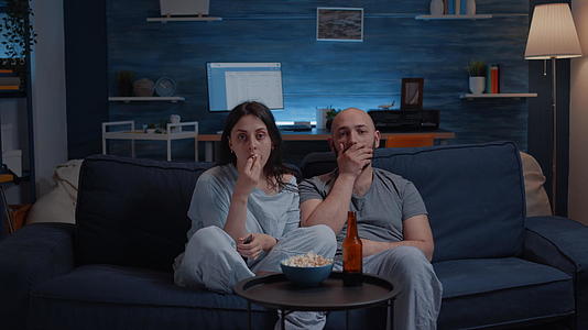 晚上一对奇怪的夫妇在电视上看电影吃爆米花视频的预览图