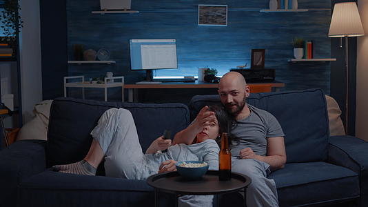 一对轻松的夫妇坐在沙发上看电视节目视频的预览图