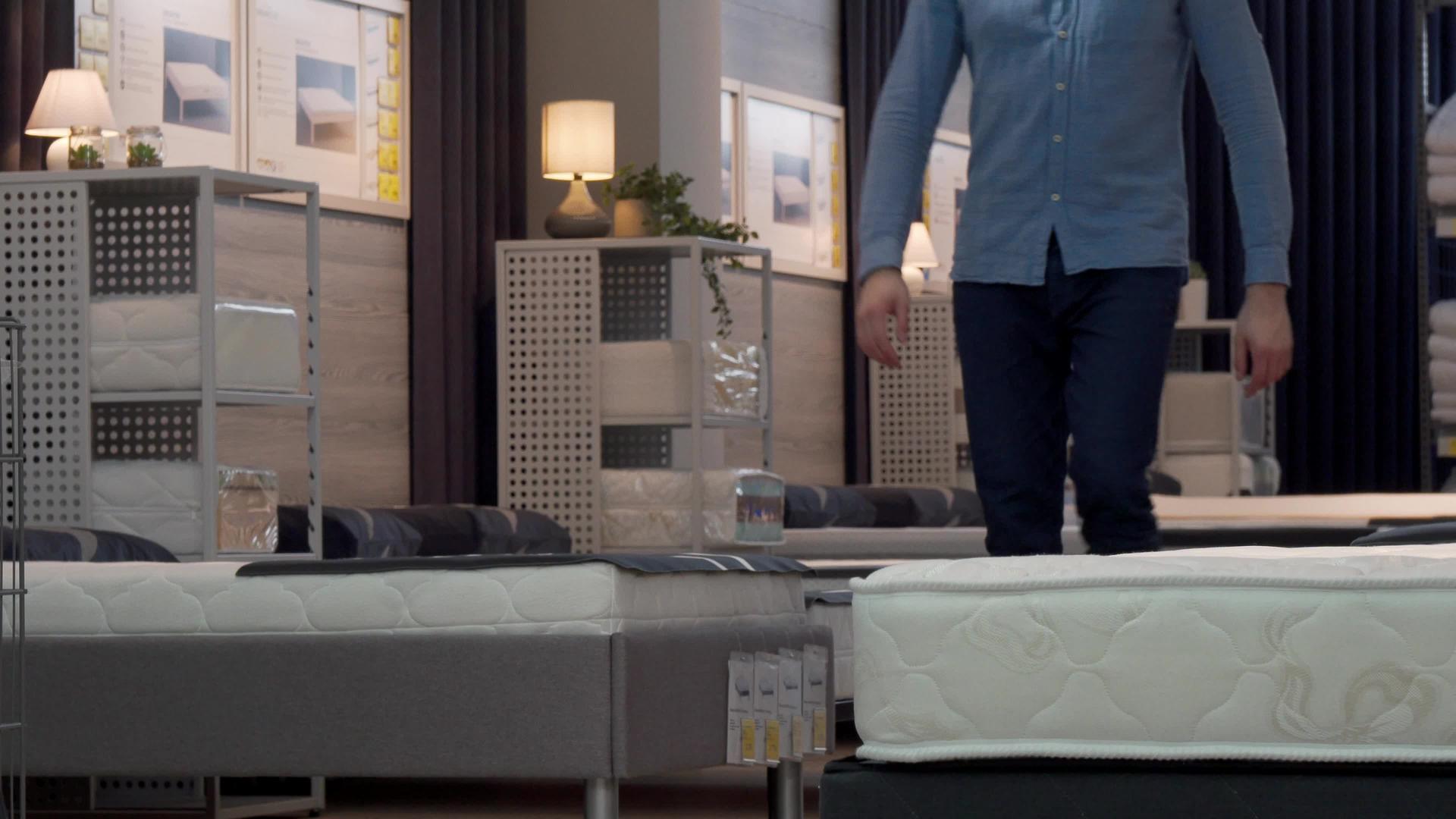 男性顾客在家具店选择塑料床垫和床视频的预览图