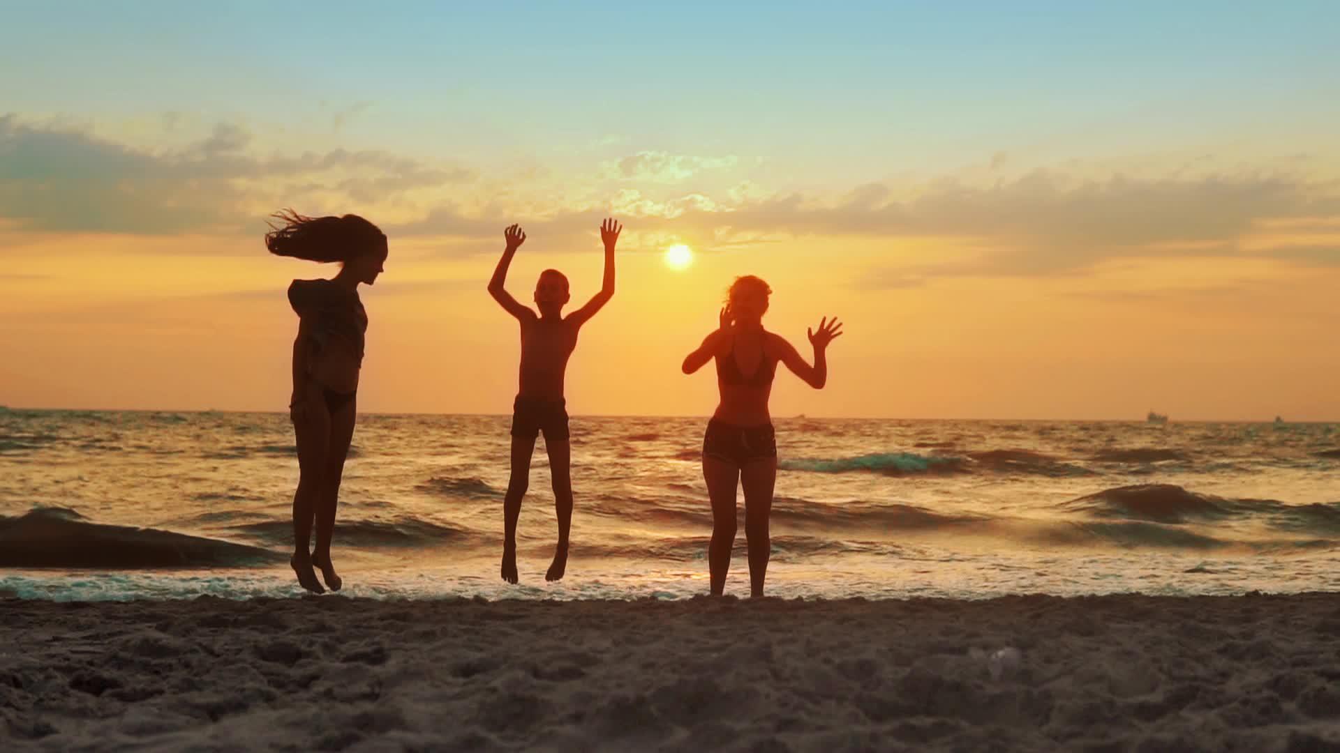 一群孩子在日落的海滩上玩耍和跳跃视频的预览图