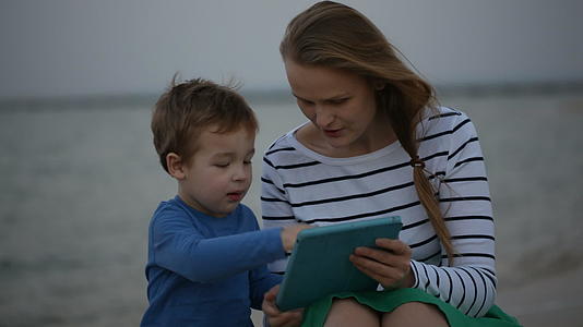 母亲和儿子在海边有垫子视频的预览图