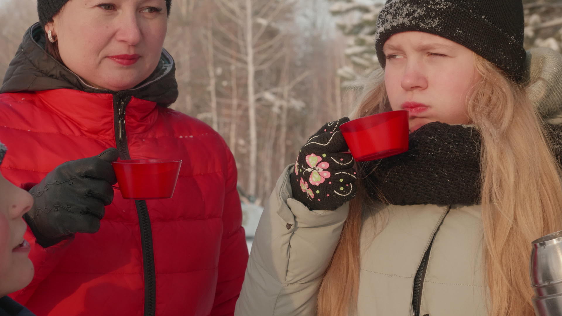寒冷的冬天一家人在雪林里漫步喝热水杯和热茶视频的预览图