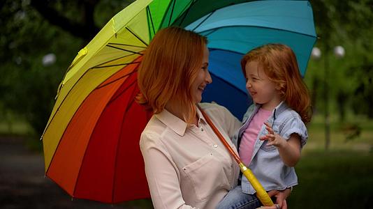快乐的母亲和女儿在五颜六色的雨伞下视频的预览图