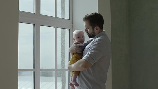 爸爸把孩子抱在窗户旁边视频的预览图
