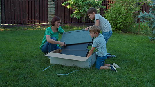 在阳光明媚的日子里两兄弟帮助年轻的单身母亲在后院组装视频的预览图
