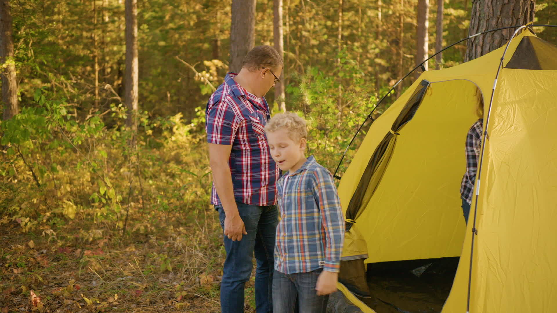 一个孩子的家庭在美丽的森林里的黄色帐篷附近视频的预览图