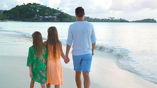 享受夏季热带海滩度假的家庭在海滩上慢慢散步视频的预览图