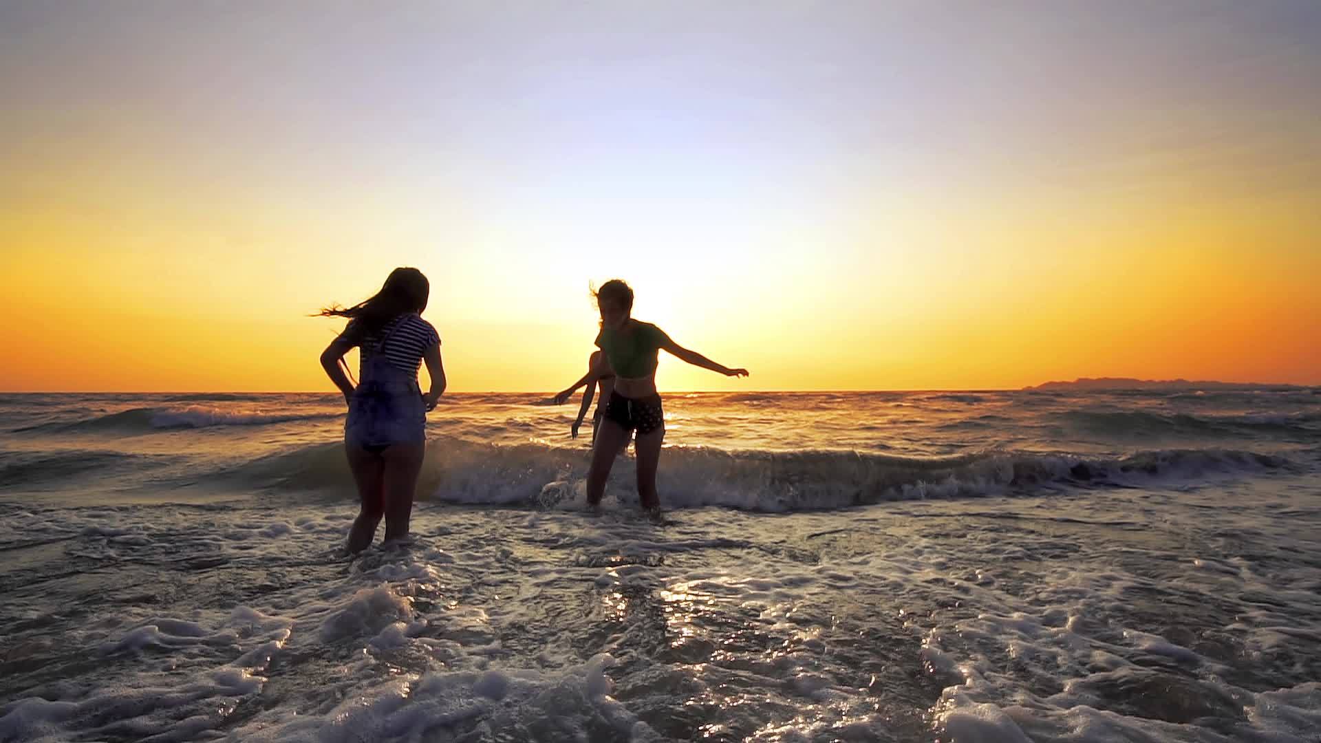 一群女孩在日落时玩得很开心跳下海滩慢慢地走着视频的预览图