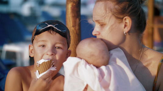 母亲和长子在海滩男孩吃冰淇淋时生了孩子视频的预览图