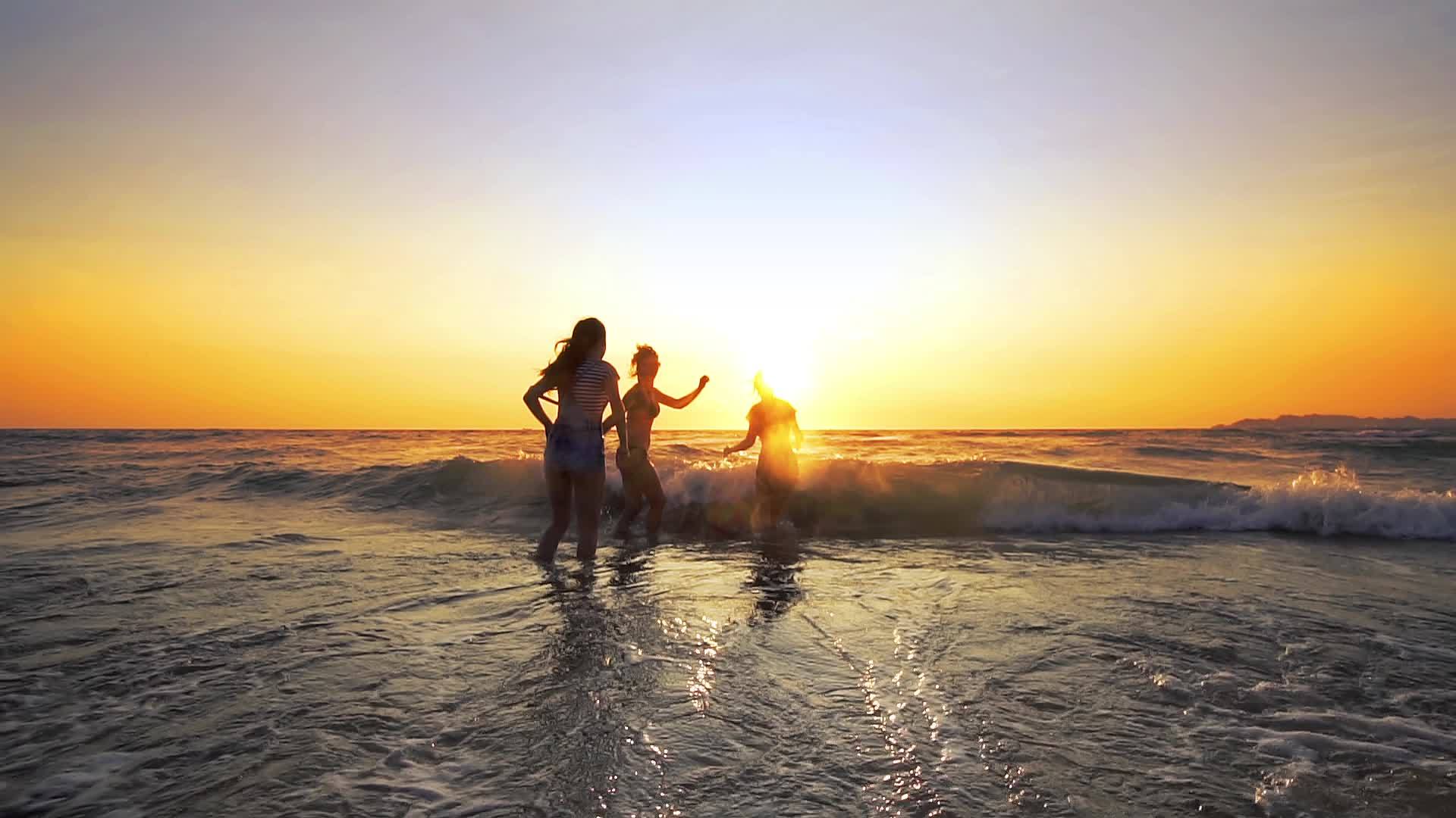 三个女孩在日落的海滩上跳舞庆祝慢动作视频的预览图