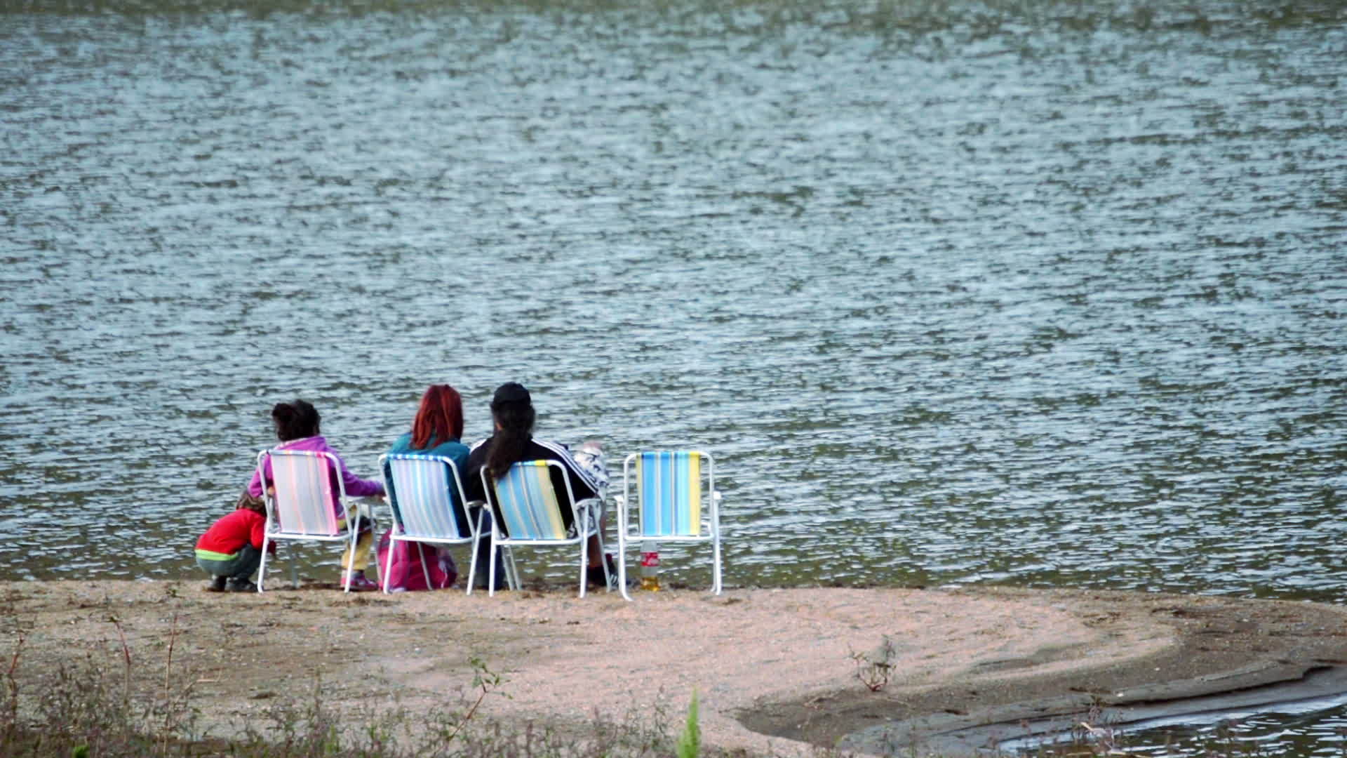 一家人坐在湖边的椅子上视频的预览图