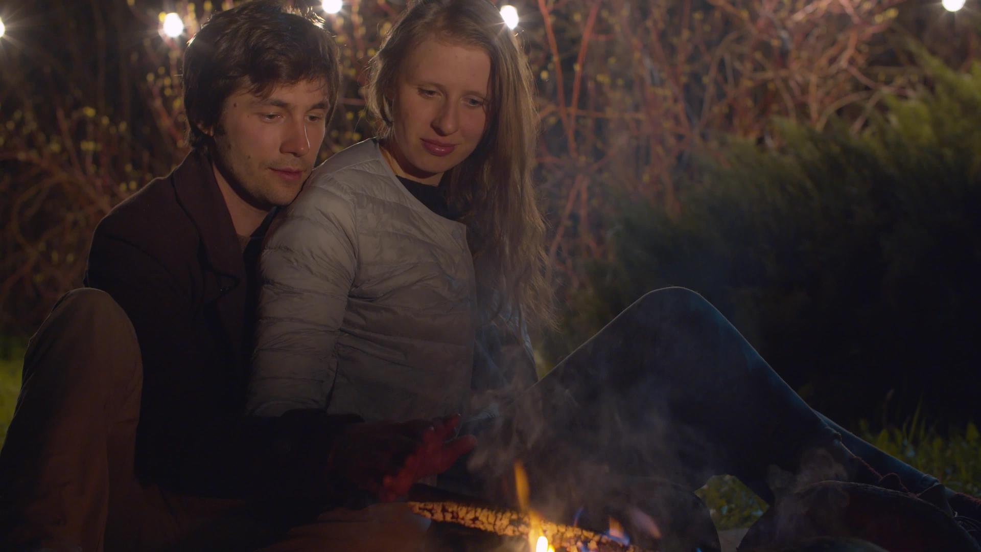 一对幸福的夫妇坐在营火附近拥抱视频的预览图
