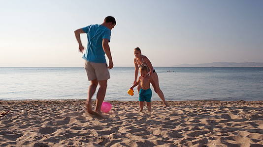 年轻的家庭在海滩上踢足球视频的预览图