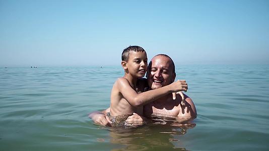 父亲和儿子在海滩上拥抱、微笑和亲吻视频的预览图
