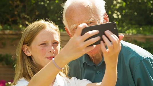 老人和他的孙女用智能手机自拍视频的预览图