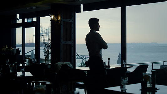 沉思的男人剪影独自站在餐厅大厅里视频的预览图