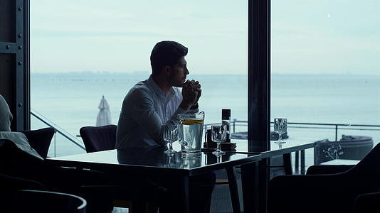 男士剪影看上去美丽的海景放松豪华全景餐厅视频的预览图